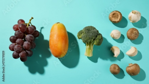 Assorted fresh fruits and vegetables arranged on a teal background