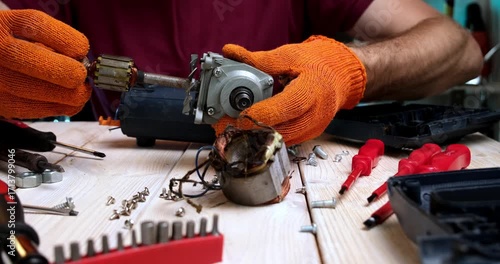 Repair of power tools. A master in a repair shop repairs a power tool