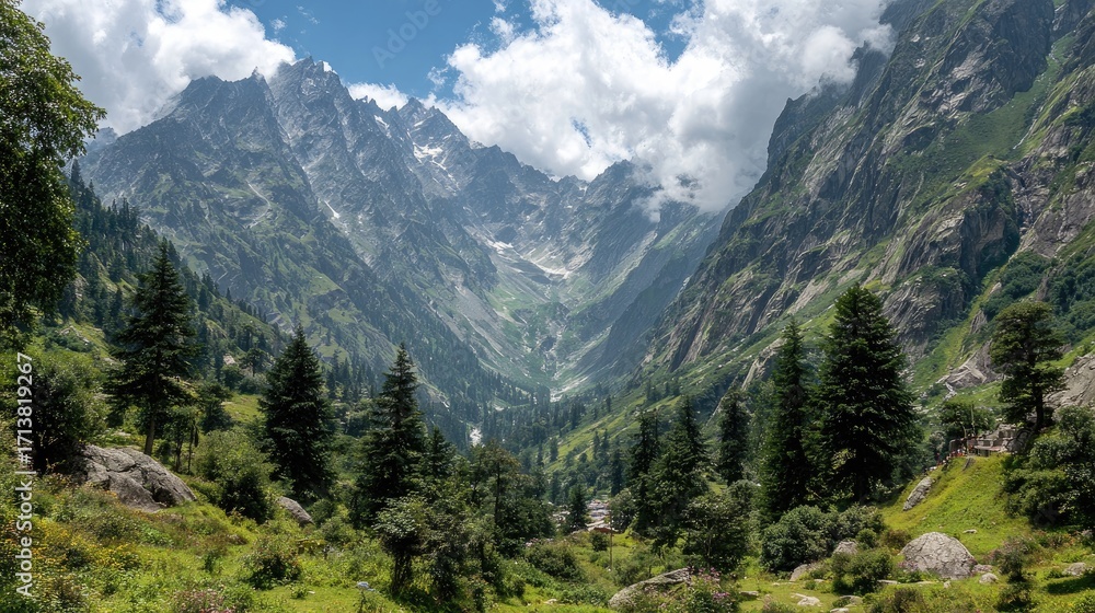 Fototapeta premium Lush green valley nestled between towering, snow-capped mountains under a partly cloudy sky