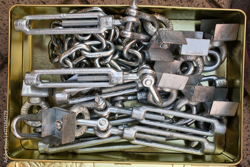 A tin of assorted metal objects, including chains and bolts