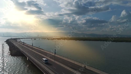 Wallpaper Mural Epic 4K drone shot of a bridge lit by sun rays breaking through clouds, with ocean, city skyline, and mountains in view. Ideal for cinematic edits. Torontodigital.ca