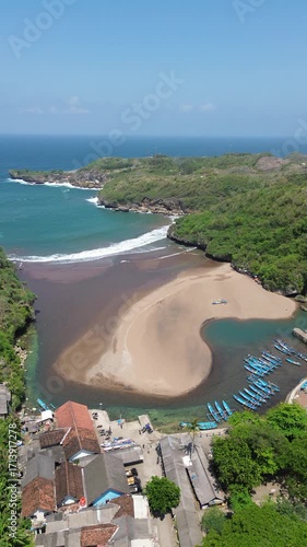 Scenic Coastal View with Lighthouse, Beach, Village, and Boats