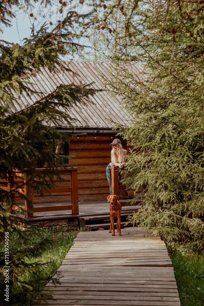 Fototapeta premium A woman is standing on a charming wooden porch along with a dog