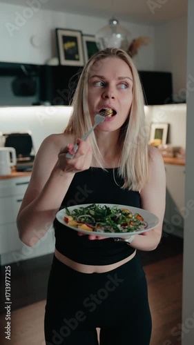 Vertical screen: caucasian woman enjoying nutritious salad in bright, modern kitchen setting, savoring fresh, colorful ingredients with mindful eating approach. Woman consuming healthy salad