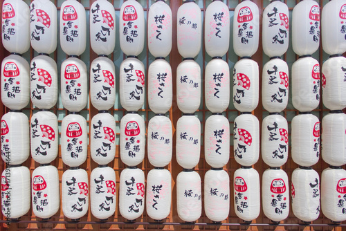 Traditional Japanese paper lanterns with Daruma doll and calligraphy designs, symbolizing culture, celebration, and spiritual charm, often seen at festivals and shrines in Japan.