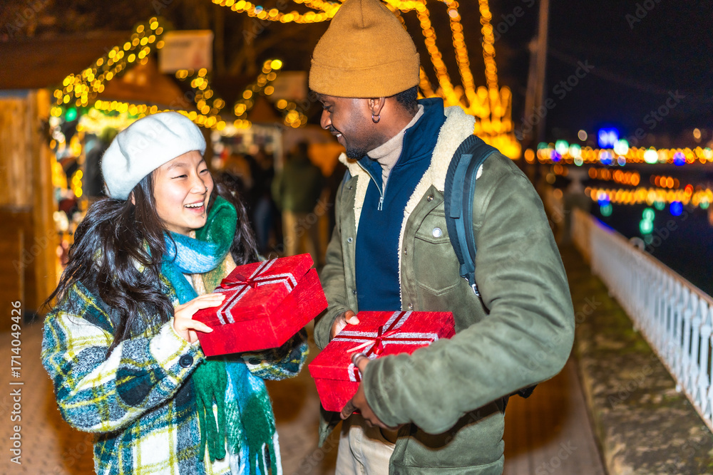 Obraz premium Happy multiethnic couple exchanging christmas gifts at market