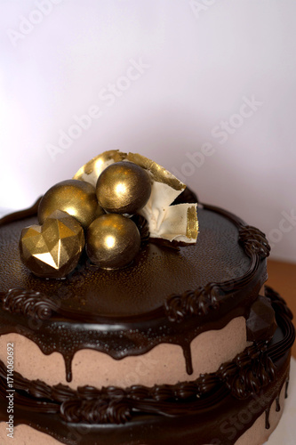Bild auf Leinwand Chocolate cake topped with glossy ganache, golden edible spheres, and geometric decorative topper