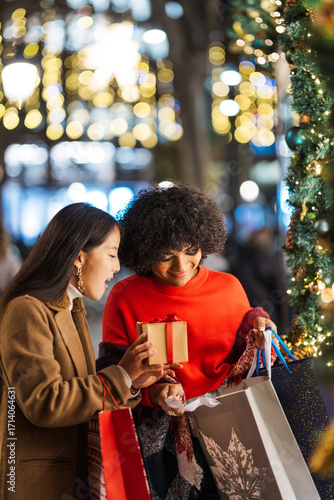 Diverse women friends exchanging christmas gift while shopping