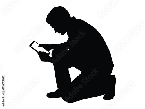 Silhouette of a person kneeling and using a tablet computer