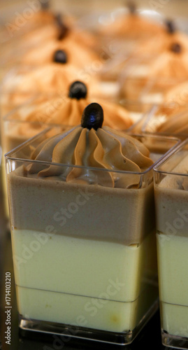 Foto Layered mousse dessert in square transparent cups, topped with piped cream and chocolate decoration