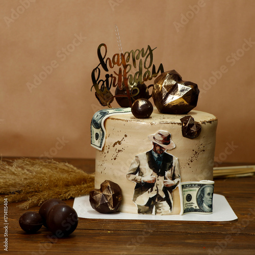 Photography Stylish birthday cake in beige and brown tones decorated with printed dollar bills, chocolate spheres, and golden happy birthday sign