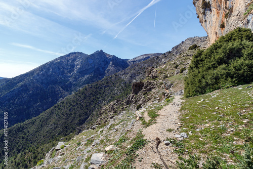 Hiking trail with an imposing cliff and panoramic views of the valley 