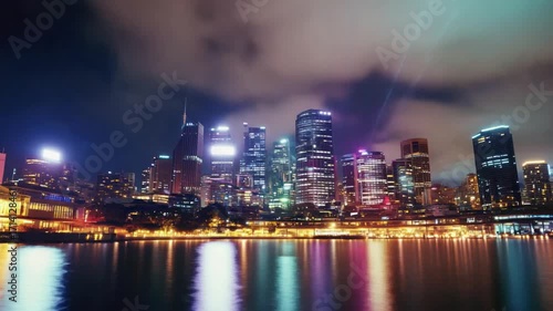 Wallpaper Mural Night cityscape featuring lit buildings reflecting in water under a cloudy sky Torontodigital.ca