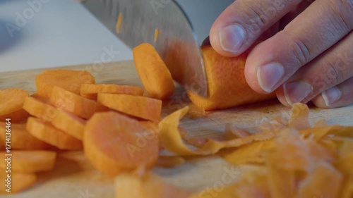 Mans hands chopping carrot on cutting board