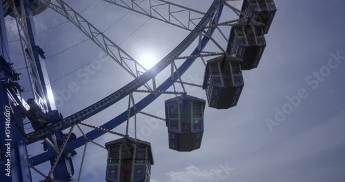 Close up Ferris wheel rotating in front of blue sky with beautiful sun reflections, Oktoberfest, Munich