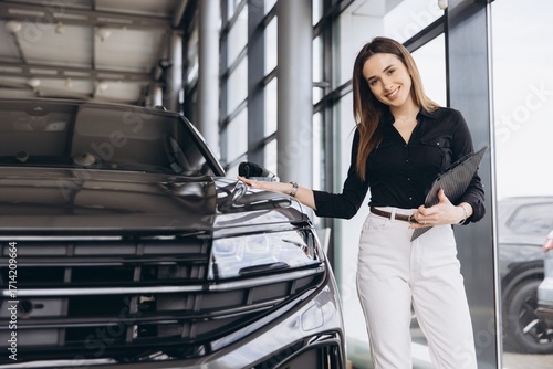 Woman presenting new car at dealership showroom