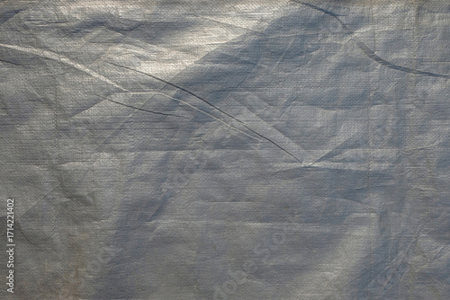 Abstract textured background of a wrinkled silver tarpaulin surface. Copy space for text. For graphic design, 3D rendering and banners