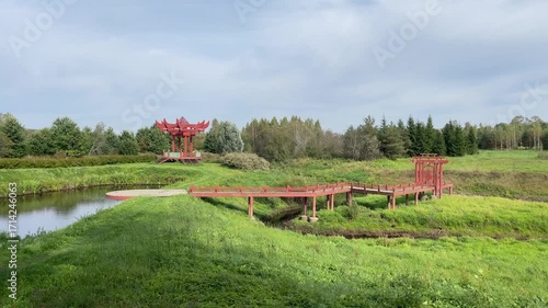 A Serene Landscape Featuring a Charming Red Pavilion and a Beautiful Wooden Bridge