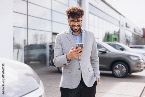 Arab man using phone at car dealership