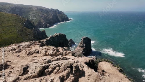 Rocky cliffs drop steeply into the Atlantic Ocean at Cabo da Roca, the westernmost point of Europe. The rugged landscape and endless blue sea create a dramatic and wild coastal atmosphere