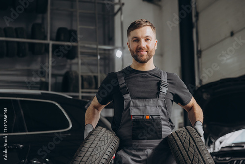 Auto mechanic holding car tires at garage
