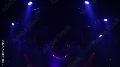 Ceiling-mounted lighting in a dark nightclub. A large sparkling disco ball, strobes, and other fixtures suspended from metal trusses.