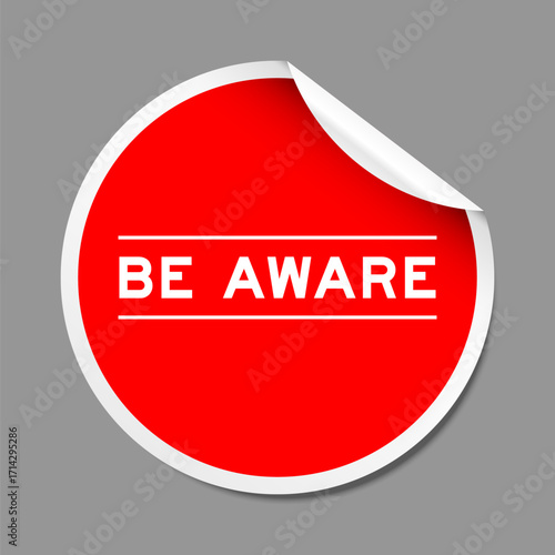 Red color peel sticker label with word be aware on gray background