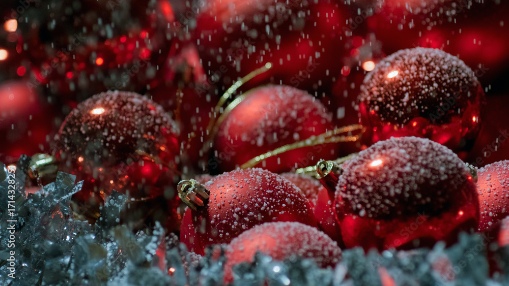 Obraz premium Christmas scene with snow falling on red tree balls decorations, close up shot. Happy New Year concept.