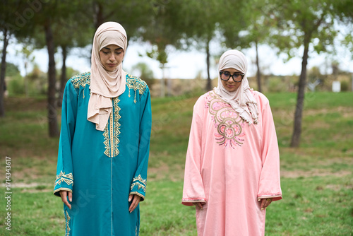 фотографія Muslim women praying outdoors wearing traditional djellabas