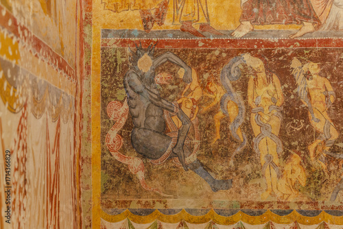View of ancient walls adorned with vibrant, fading frescoes depicting figures and patterns, a visual story etched in time, Bominaco, Abruzzo, Italy.