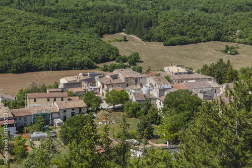 Wallpaper Mural View of the Italian village nestled between the green trees and the brown field, a serene landscape under a clear sky, Bominaco, Abruzzo, Italy. Torontodigital.ca
