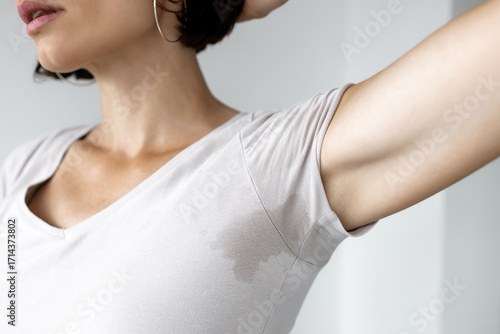 Woman checking sweat stain under armpit on her t-shirt, concept of excessive sweating, body odor and hyperhidrosis problem in adult female 