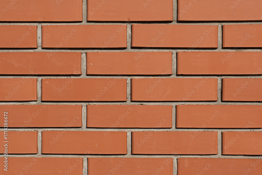 Obraz premium Orange brick wall texture with mortar lines, seamless architectural background for construction and design with copy space.