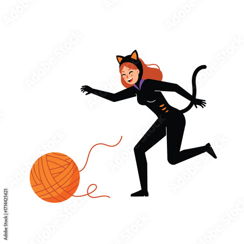 A woman dressed as a cat playfully chases a large ball of orange yarn.