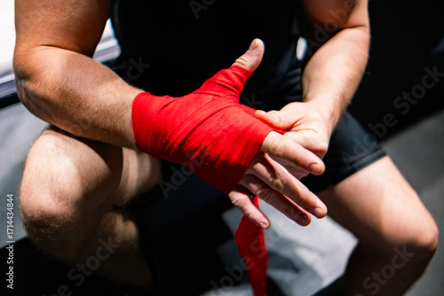 The man ties a red boxing hand wraps around his wrists. Preparing before the box fight. Boxing bandage.