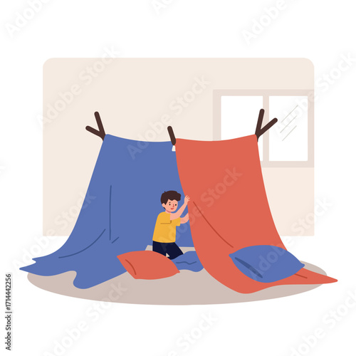 Boy plays in a homemade fort inside, sticks support colorful fabric with pillows inside
