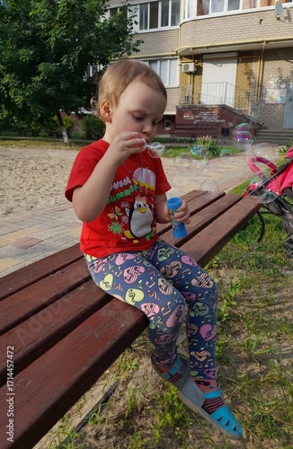 little girl sitting on a bench in park