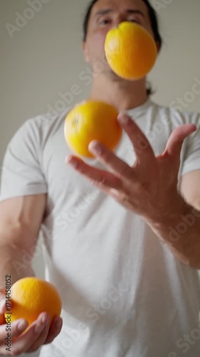 Caucasian man having fun, funny playing with fruits at home, juggling oranges. Slow motion