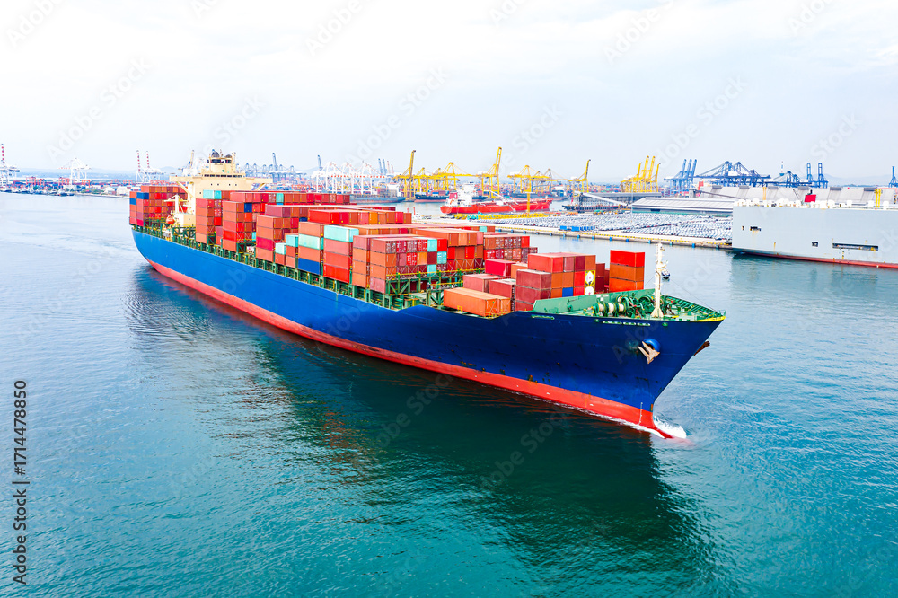 Fototapeta premium Aerial view of international cargo containers ship at industrial import-export port prepare to load containers with big container loader ship vessel at night. global transportation, logistic business