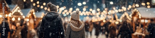 As snow falls, a couple strolls through an outdoor Christmas market at night, bathed in the warm glow of festive lights, creating a magical winter scene.