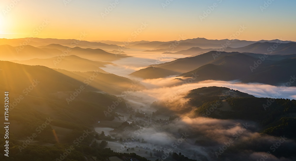 Fototapeta premium Sunrise over mist-covered mountain ranges with golden light illuminating valleys and hills