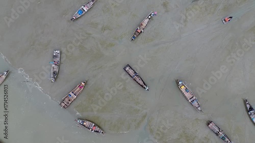 drone footage circles many boats on the receding shore