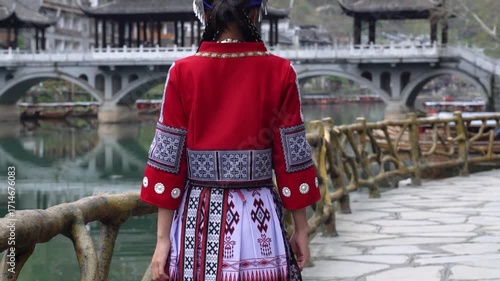 Woman in Traditional Miao Dress Walking on Ancient Stone Bridge in Historic Chinese River Town