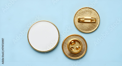 A top-down view of blank circular golden lapel pins on a light blue background.