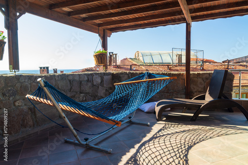 Empty hammock on hotel terrace in Assos Turkey overlooking Mediterranean sea, melancholic end of summer atmosphere with abandoned vacation spot and lonely mood