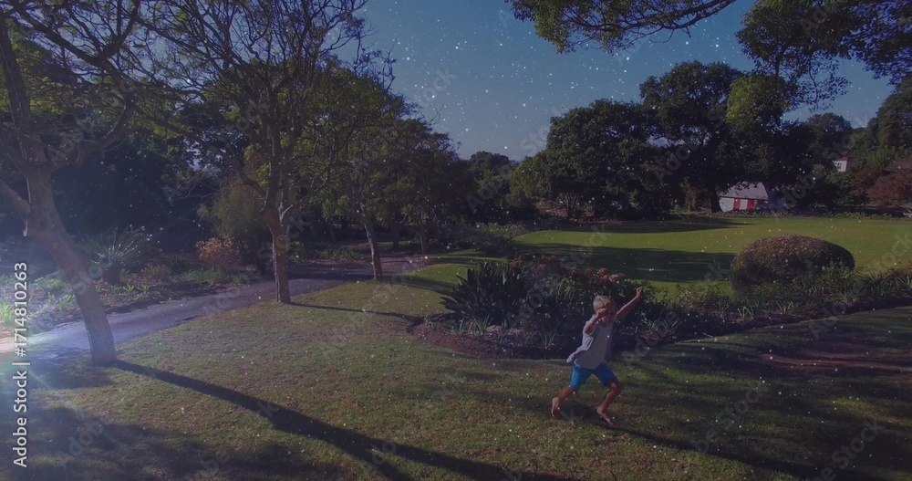 Obraz premium Walking barefoot boy wearing blue shorts crossing path at park near cottage under stars, copy space
