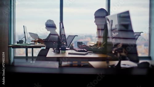 Busy corporate office silhouettes at cityscape window closeup. People working