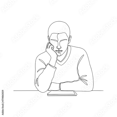 Bored young man resting chin on hand with tablet on desk