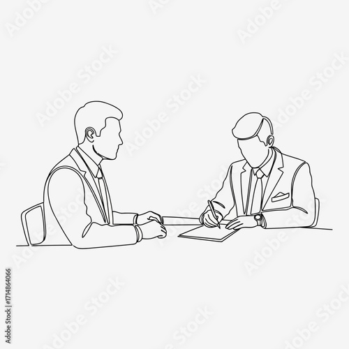 Two businessmen in suits at a table one writing on paper