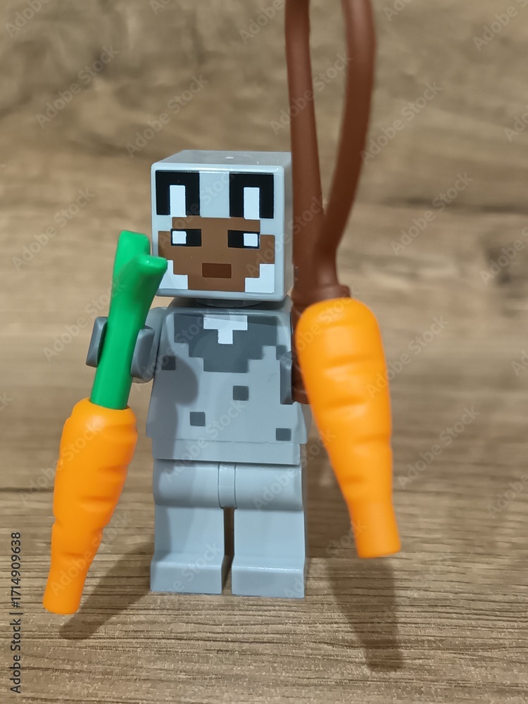 Naklejka premium Whimsical block figures a pink pig-like character with a golden weapon and a grey animal holding a fresh carrot, posed on wood, symbolizing fantasy play and imaginative adventure